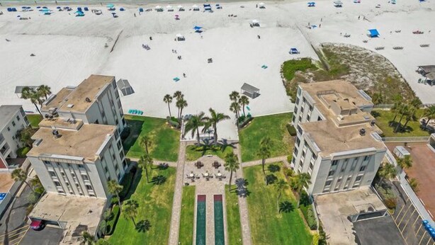 An aerial view of a beachfront hotel with multiple buildings, a sandy beach with umbrellas, and a central green area with a pool. - Island House Beach Resort 14N (Siesta Key)