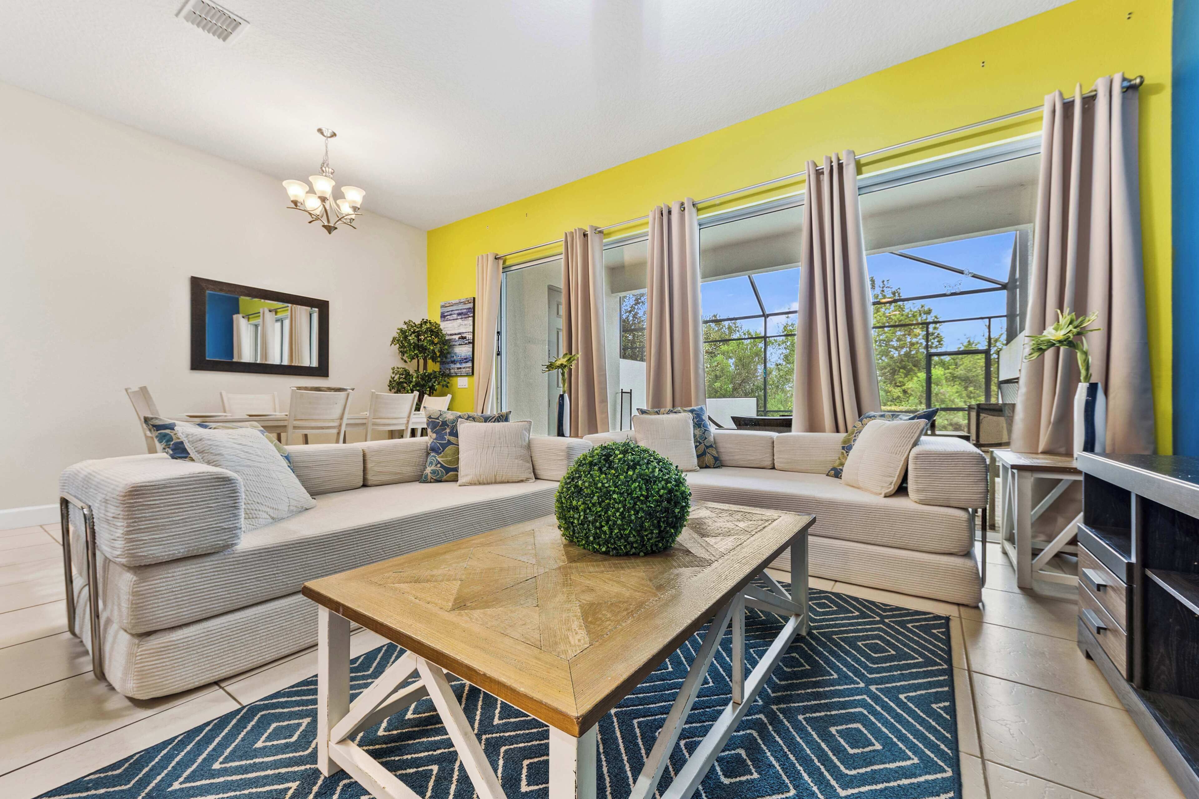 A modern living room with a sectional sofa, a coffee table, and a large window with curtains.