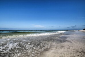 Een strand met helder water, een zandstrand en een heldere lucht.
