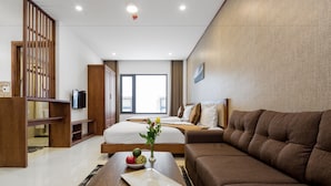 Una habitación de hotel moderna con una cama grande, un sofá marrón, un escritorio de madera y una televisión.