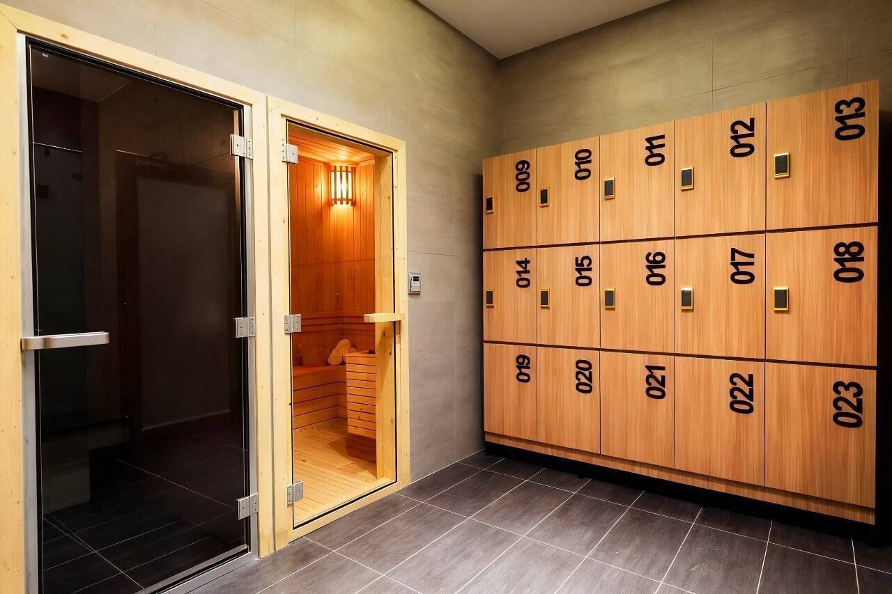 A hotel room with a sauna, a glass door, and wooden lockers with numbers.