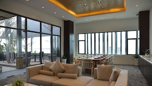 A spacious lobby with a large sofa, dining area, and large windows offering views of the city. - The View Serviced Residence (Phnom Penh)