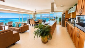 Una cocina moderna con vista al océano, un comedor con vistas y una sala de estar con una planta grande.