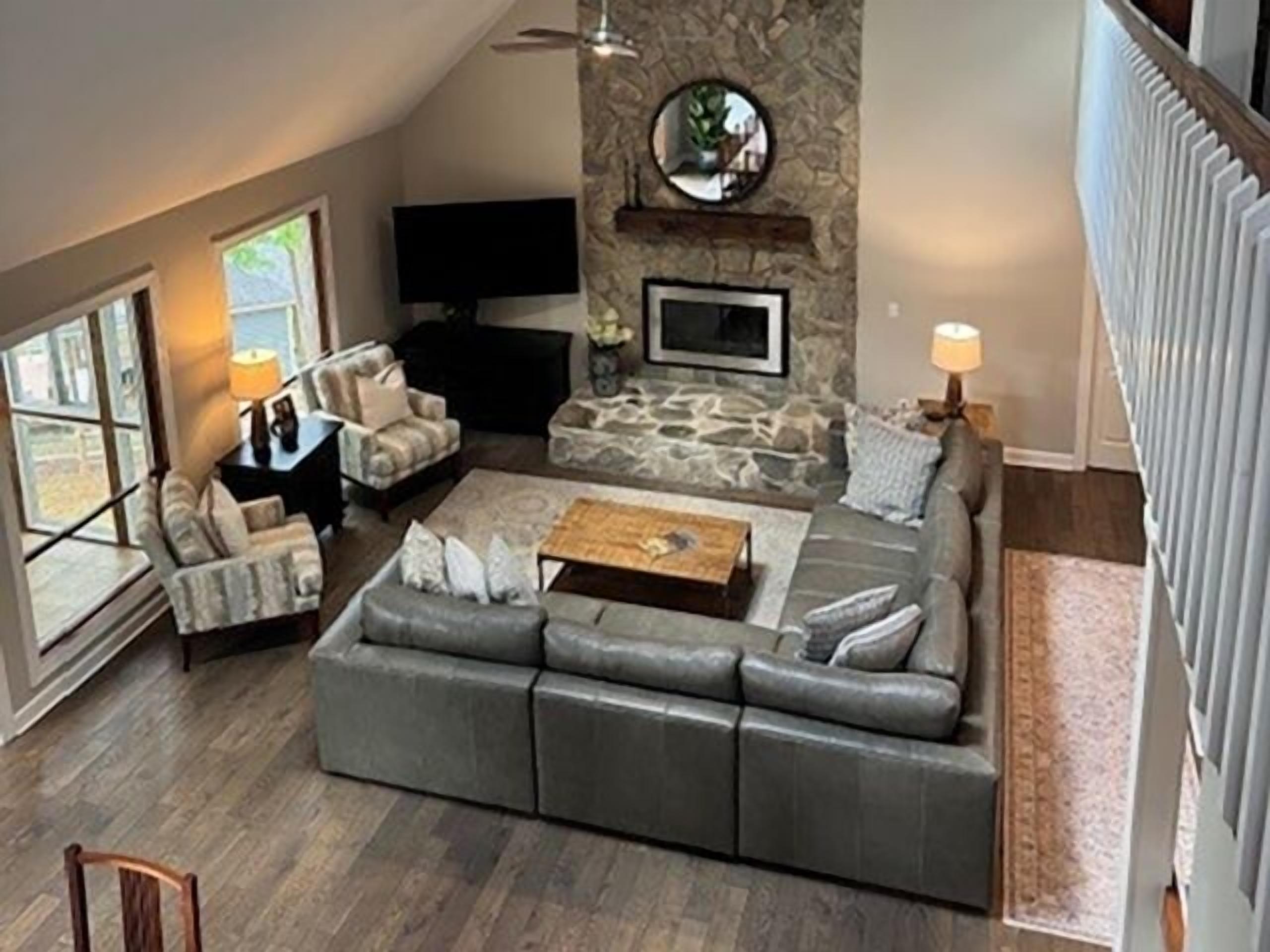 A living room with a stone wall, a flat-screen TV, a sofa, a coffee table, and a fireplace.