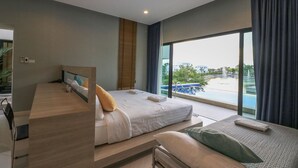 Ett modernt hotellrum med ett stort fönster som erbjuder utsikt över en swimmingpool och stadens skyline. Rummet har en stor säng, ett skrivbord och en stol.