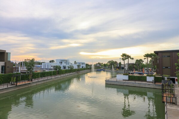A canal with a fountain, surrounded by modern buildings and greenery.