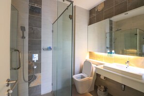 A modern bathroom with a glass-enclosed shower, a white toilet, and a large mirror above a white sink.