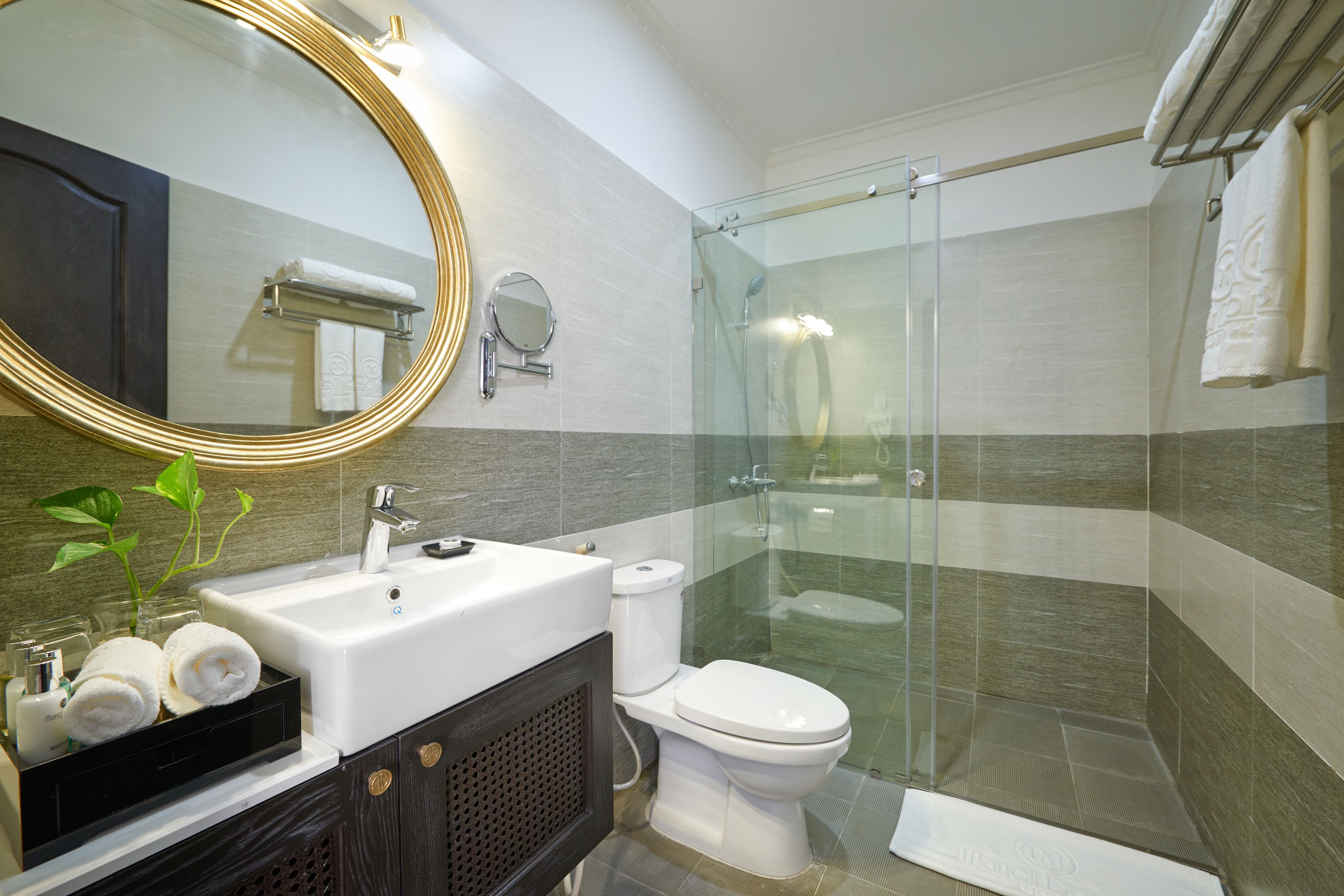 A modern bathroom with a sink, mirror, toilet, and glass-enclosed shower.