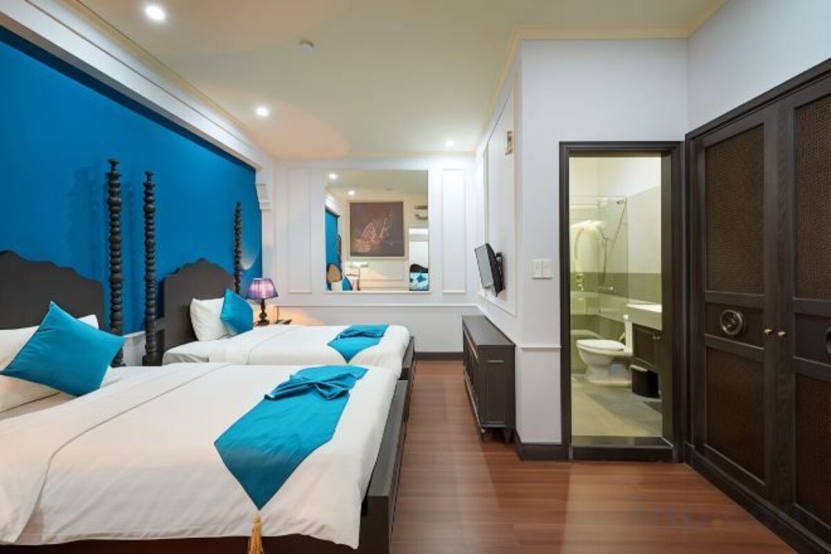 A hotel room with two beds, a bathroom, and a view of the city.