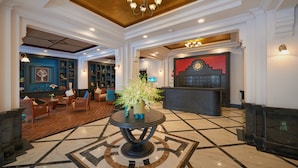 A lobby with a marble floor, a reception desk, and a seating area with chairs and a table.
