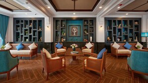 A spacious lobby with wooden flooring, a central coffee table, and seating arrangements including sofas and chairs.