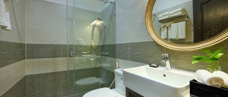 A modern bathroom with a glass-enclosed shower, a white sink, and a large mirror with a gold frame.