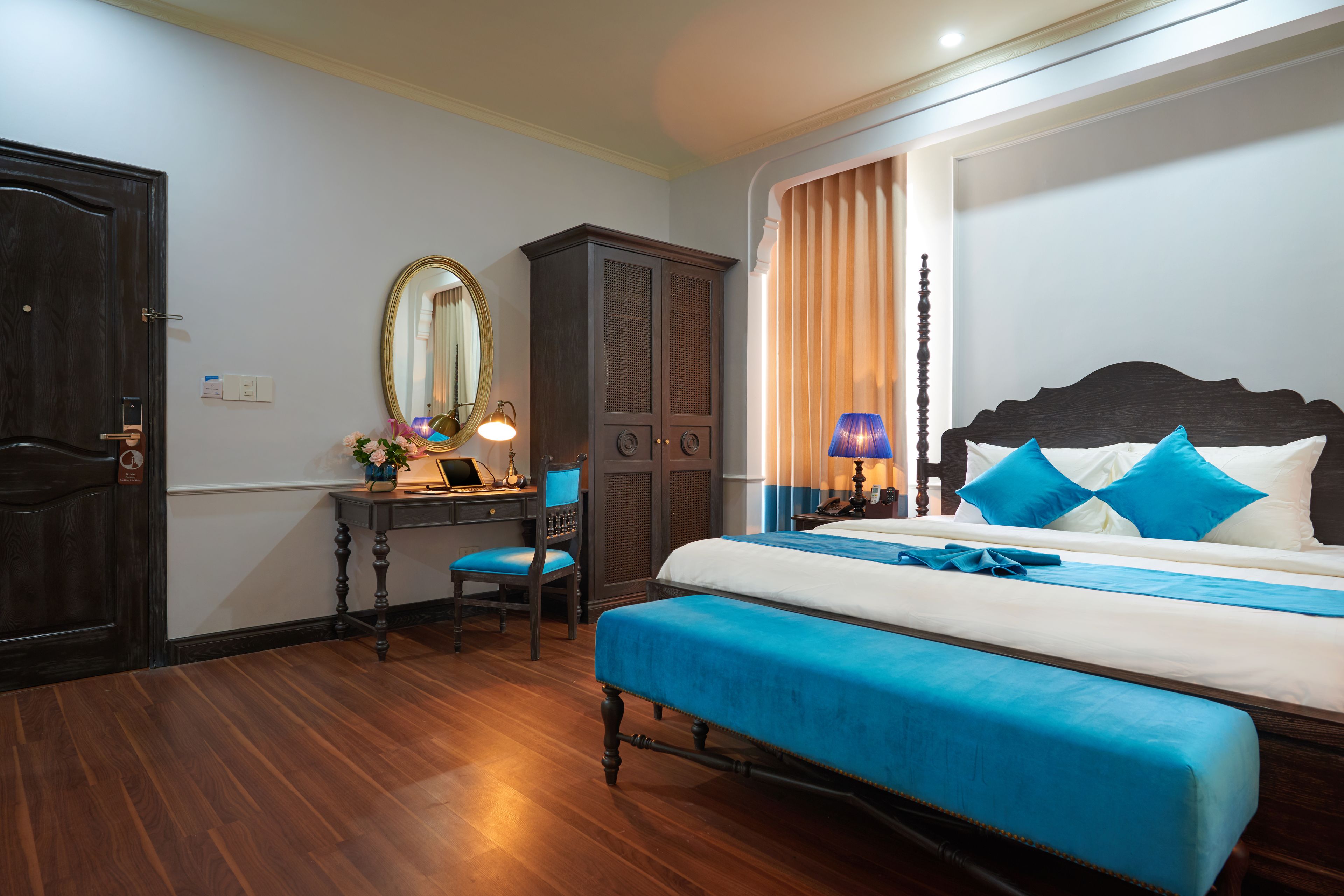 A bedroom with a bed, a desk, a chair, a wardrobe, and a mirror.