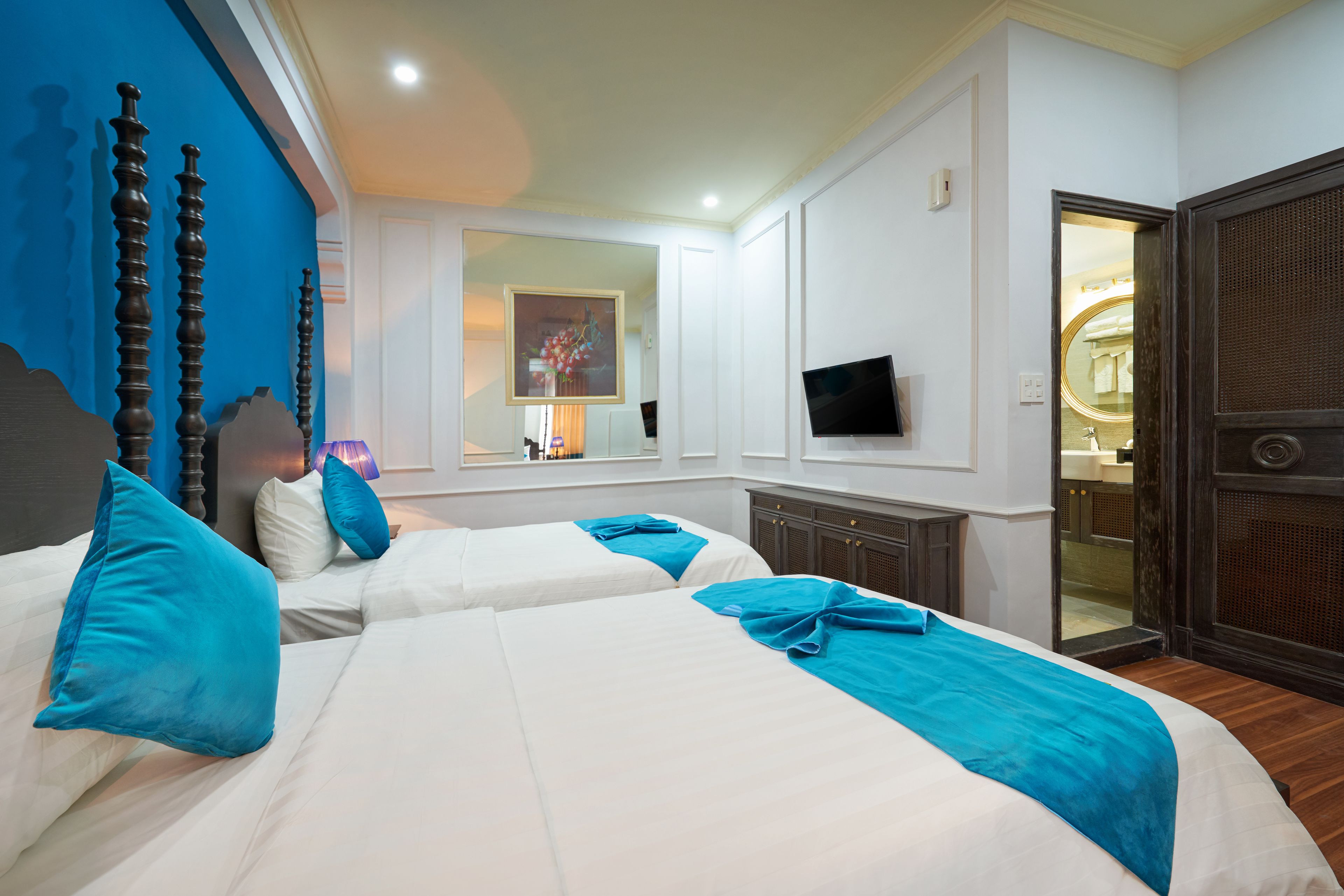 A hotel room with two beds, a TV, and a mirror.