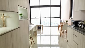 Une cuisine moderne dotée d’une grande fenêtre, de meubles blancs et d’un coin repas avec des chaises et une table.