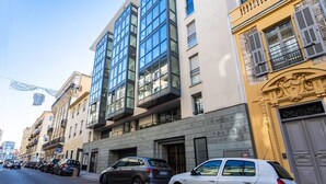 Vista d'un carrer amb cotxes aparcats, un edifici amb grans finestres i una porta amb el número 9.