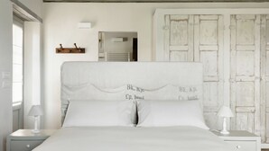 Une chambre à coucher avec un grand lit, une tête de lit en bois, une table de chevet blanche, une lampe de chevet et une armoire au style rustique.