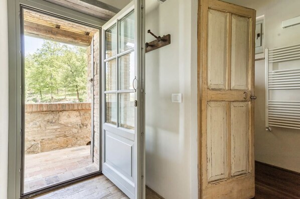 A room with a sliding glass door leading to an outdoor area with a stone wall and trees.