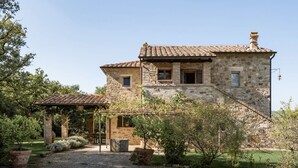 Une maison en pierre avec un toit en tuiles, un patio couvert et une allée gravillonnée.