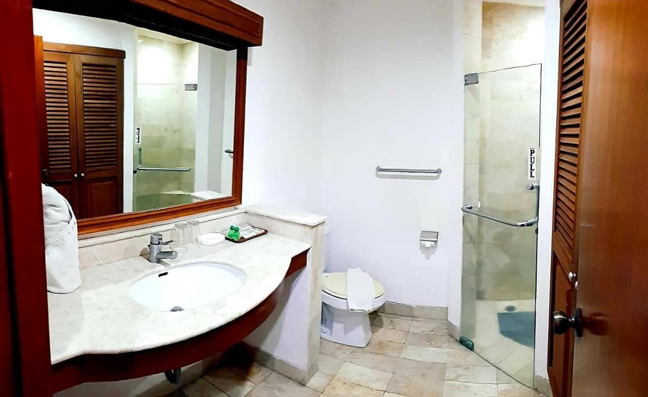 A bathroom with a marble sink, a mirror, a toilet, and a glass shower door.