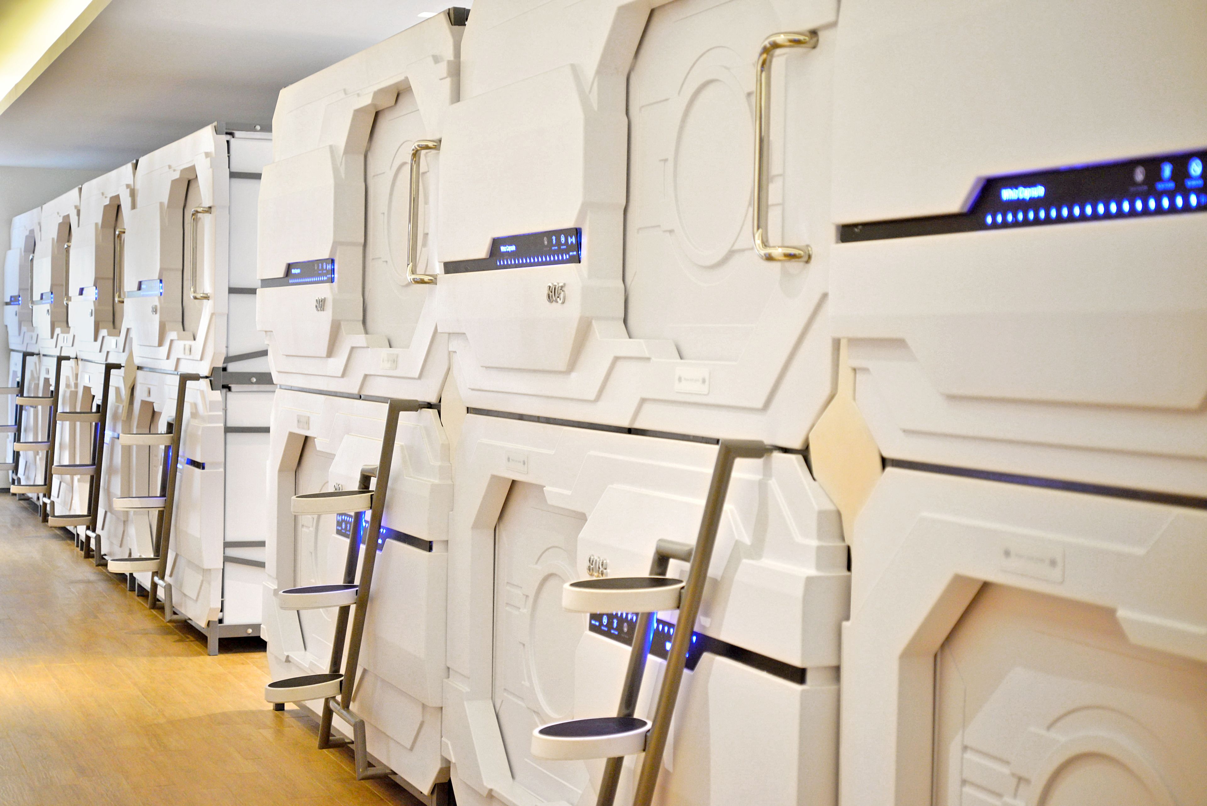 A row of white, futuristic-looking rooms with built-in control panels and metallic handles.
