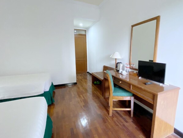 Une chambre d’hôtel comprenant un lit, un bureau avec une chaise, une télévision et un miroir.