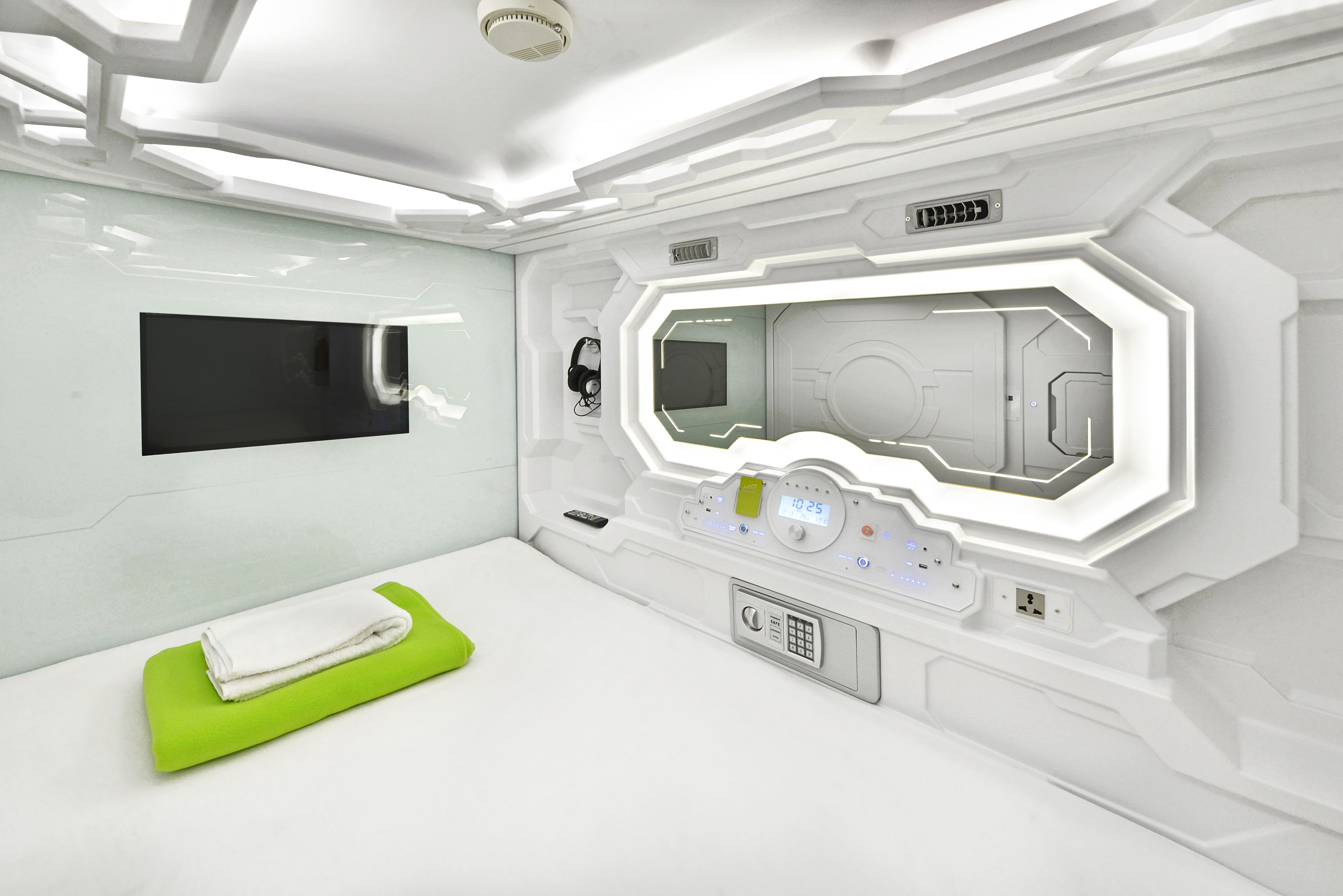 A modern, white-themed room with a large mirror, a flat-screen TV, and a green mat on the floor.