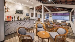 Una zona de bar con mostrador de mármol, sillas de mimbre y techo de madera.