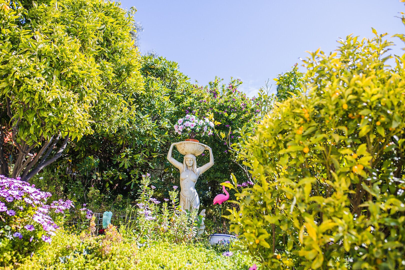 A garden with a statue of a woman holding a basket.