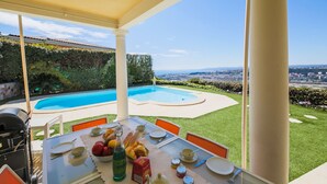 Eine Terrasse mit Pool, Esstisch und Stühlen mit Blick auf eine Stadtlandschaft.