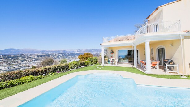 Blick vom Pool auf ein Haus, mit freiem Blick auf Stadt und Berge im Hintergrund.