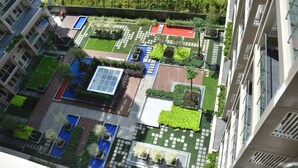 An aerial view of a modern residential building with multiple balconies, a rooftop garden, and a swimming pool.