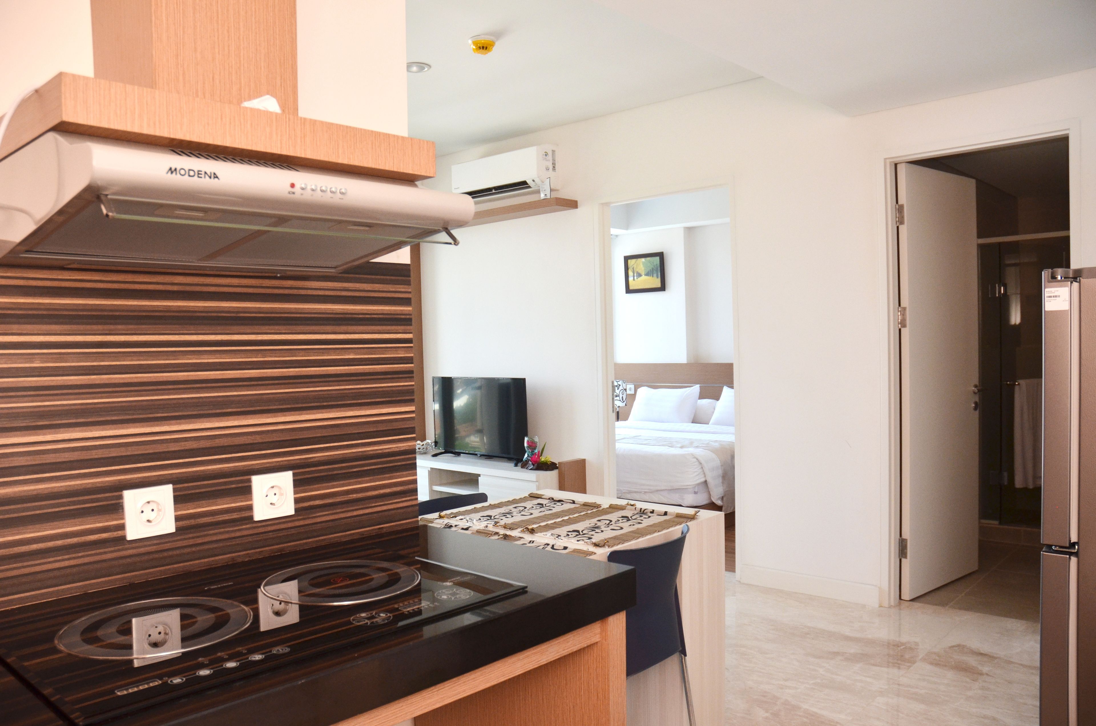 Une cuisine moderne équipée d’une cuisinière intégrée, d’une hotte aspirante et d’un téléviseur à écran plat.