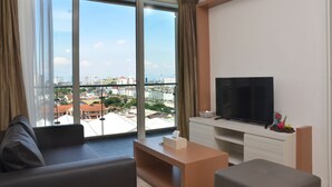 A modern living room with a large window, a flat-screen TV, and a sofa.