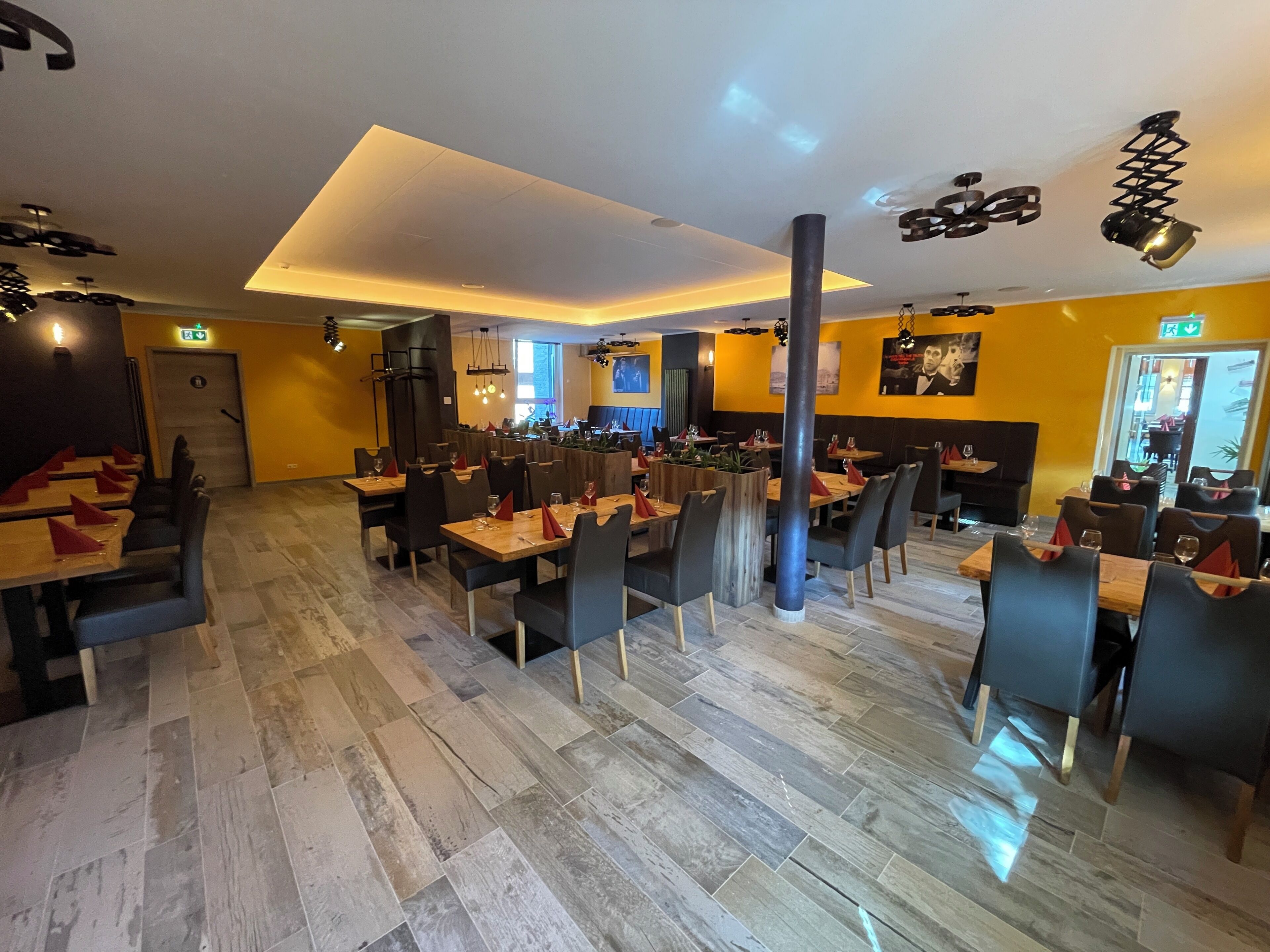 A restaurant with multiple tables, chairs, and a modern ceiling design.