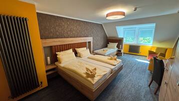A bedroom with two beds, a radiator, a window with blinds, and a desk.