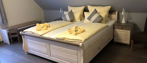 A neatly made bed with two pillows and a bedside table with a lamp.