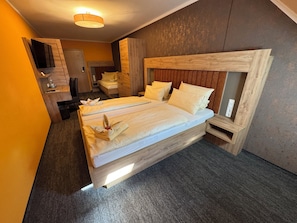 Ein Hotelzimmer mit einem großen Bett, einem Schreibtisch, einem Stuhl, einem Kleiderschrank und einem Fernseher.