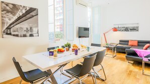 A modern living room with a dining area, featuring a white table, black chairs, a red floor lamp, and a black sofa with orange cushions. - CARRE D' OR TERRACE AP4015 by RIVIERA HOLIDAY HOME (Niza)