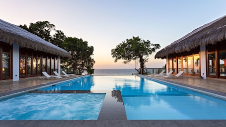 Una piscina al aire libre, sillones reclinables de piscina