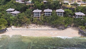 Un complexe hôtelier comprenant plusieurs bâtiments de style bungalow, entouré d’une végétation luxuriante et donnant sur une plage.