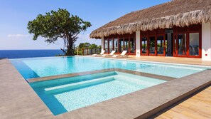A poolside area with a view of the ocean, a thatched-roof building, and lounge chairs. - Ocean's Edge Resort (Carabao Island)