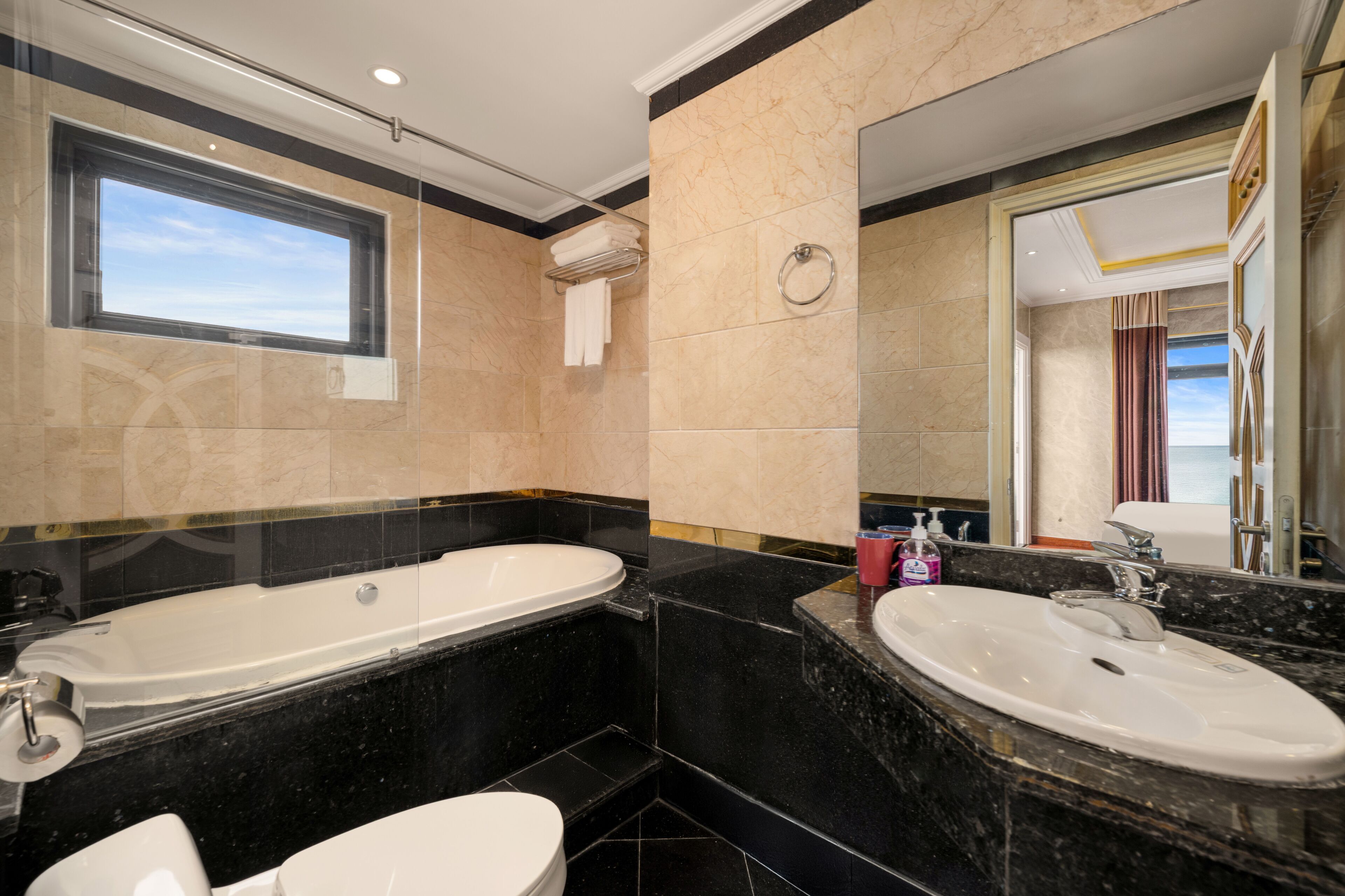 A modern bathroom with a large bathtub, two sinks, and a large mirror.