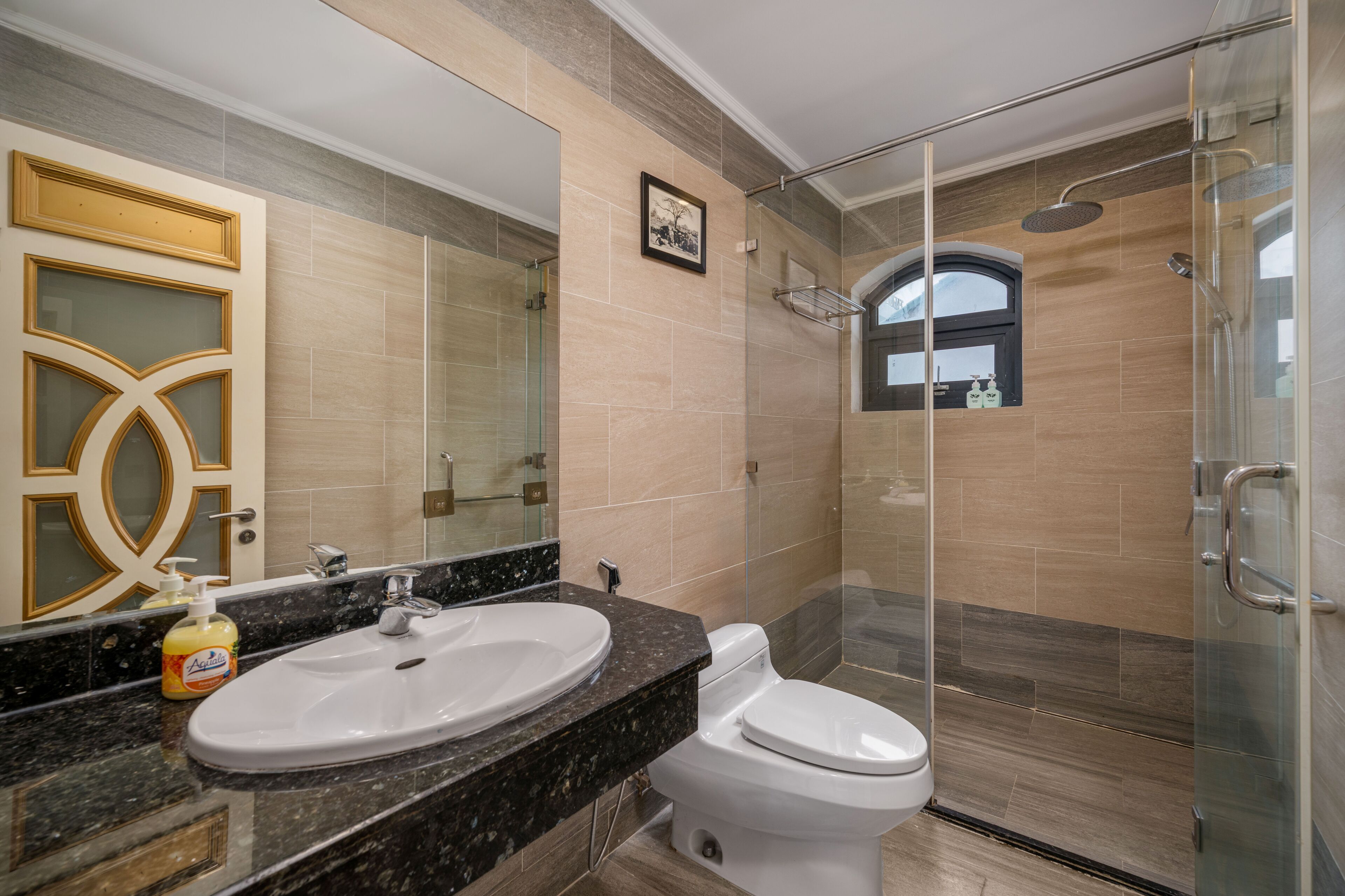 A modern bathroom with a large sink, toilet, and glass-enclosed shower.