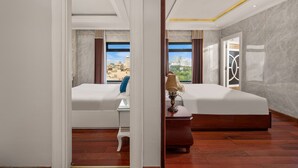 A hotel room with two beds, a desk, and a view of a cityscape.
