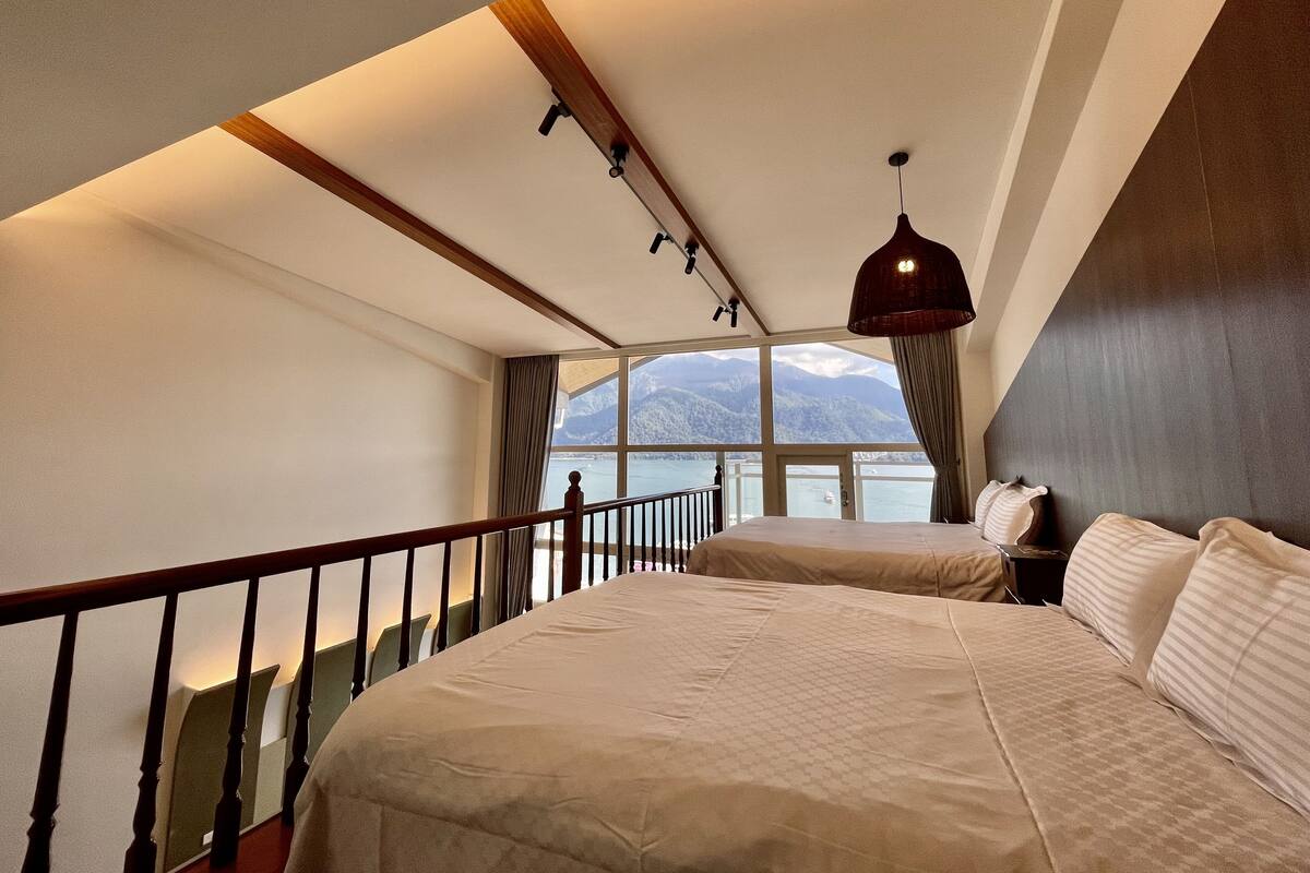 Un dormitorio con una cama grande, vistas a montañas y un balcón con barandilla.