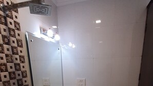A bathroom with a white sink, a mirror, a toilet, and a trash bin. - Krishna Inn (New Delhi)