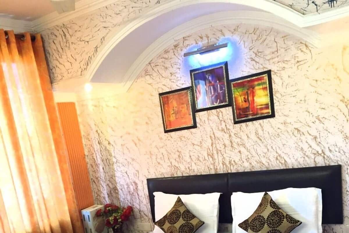 A hotel room with a large bed, a headboard, and a wall with three framed pictures.