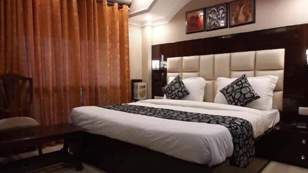 A modern bedroom with a large bed, a ceiling fan, and a chandelier. - Krishna Inn (New Delhi)