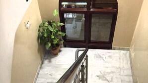 A marble staircase with metal railings leading to a door with a glass panel. - Krishna Inn (New Delhi)